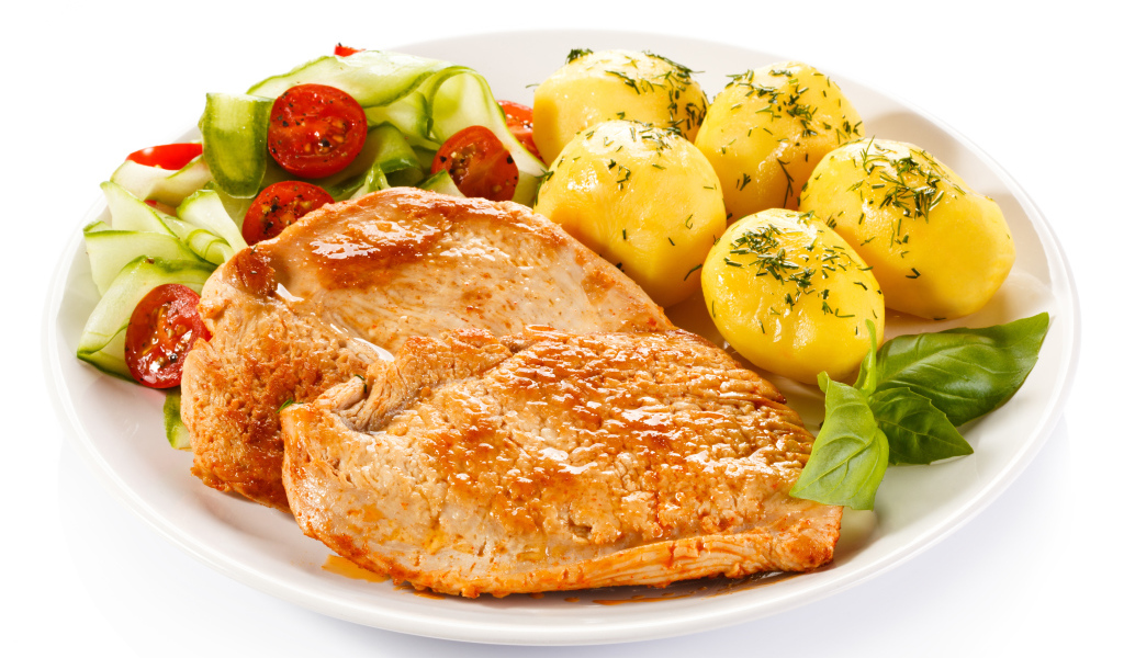Кусок сочного куриного мяса на тарелке с картофелем и салатом