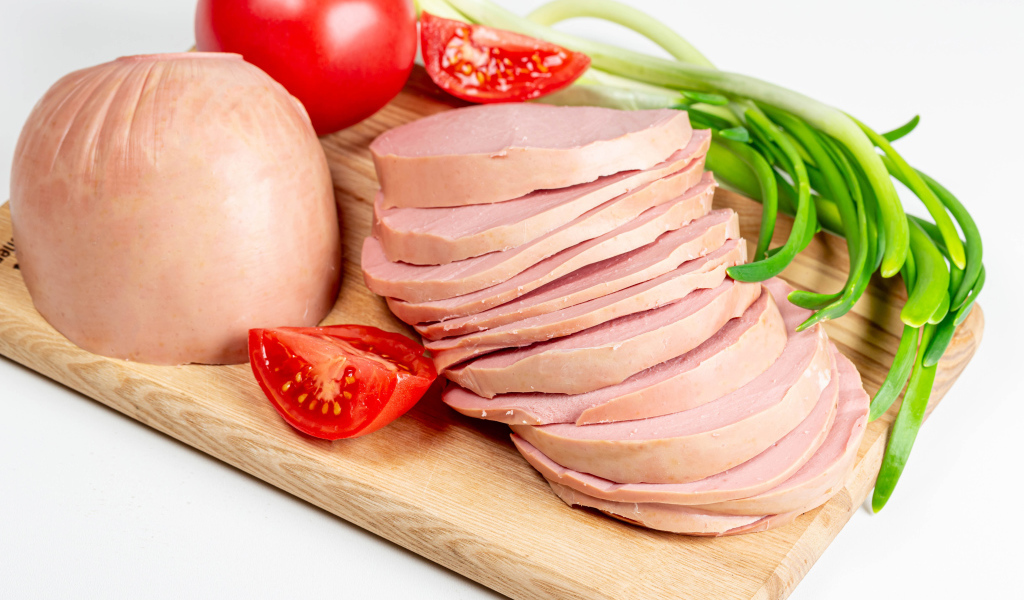 Вареная колбаса на доске с луком и помидором