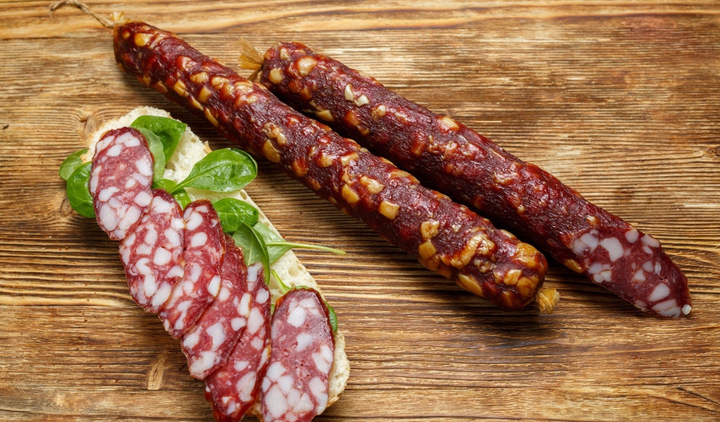 Вкусная сухая колбаса на столе с бутербродом