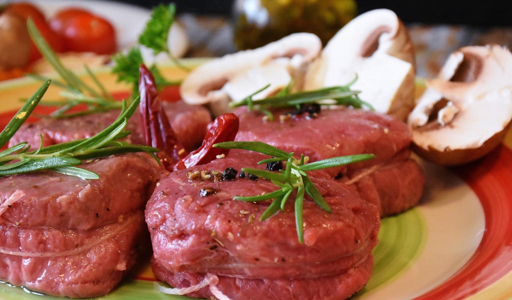 Свежее мясо маринуется со специями на столе с грибами