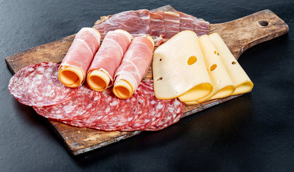 Рулеты из ветчины с сыром на столе с колбасой и мясом