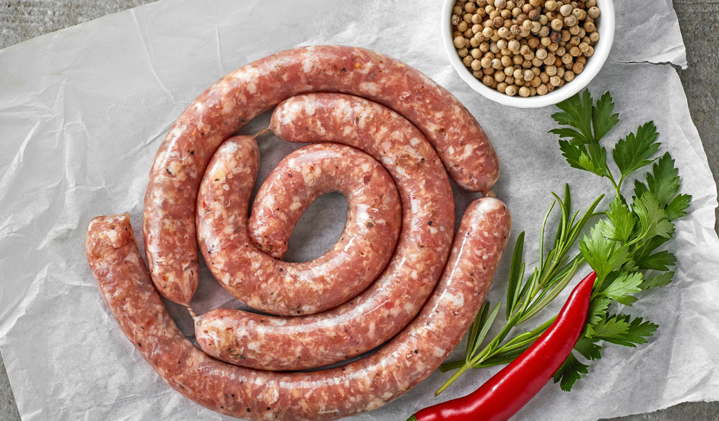 Домашняя колбаса на столе с зеленью и перцем