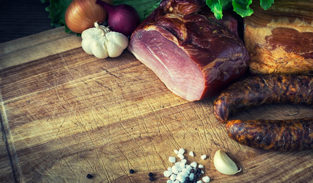 Мясные продукты на столе со специями, луком и чесноком 