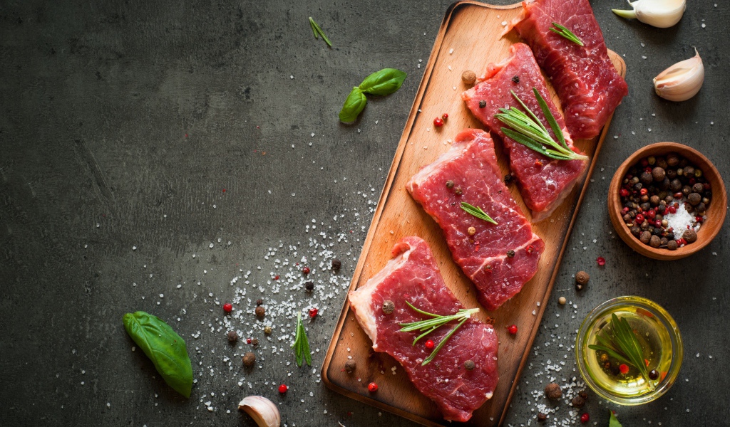 Куски мяса со специями и зеленью на доске 