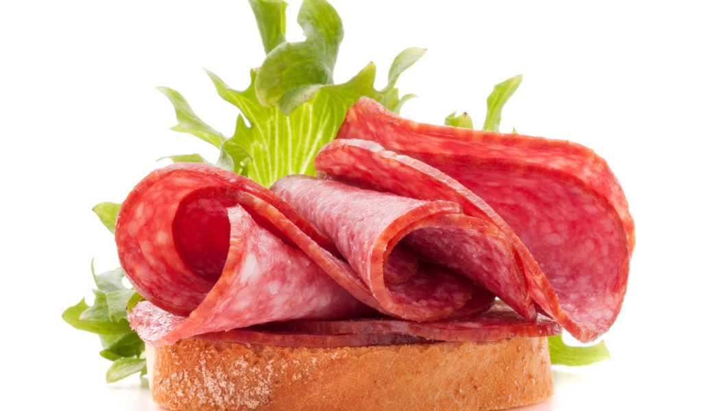 Бутерброд с листьями салата и колбасой на белом фоне