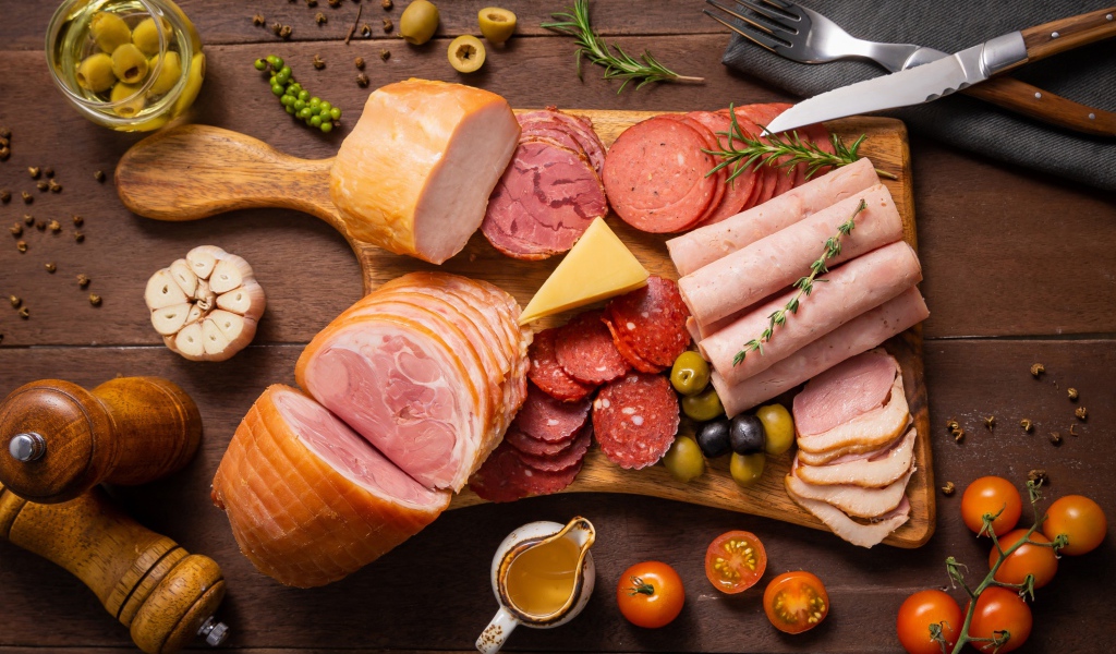 Колбасы и мясные продукты на доске со специями