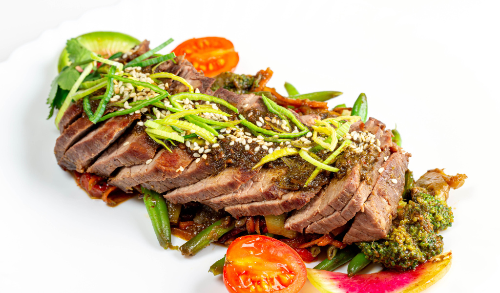 Мясо нарезанное кусочками на белом фоне с овощами