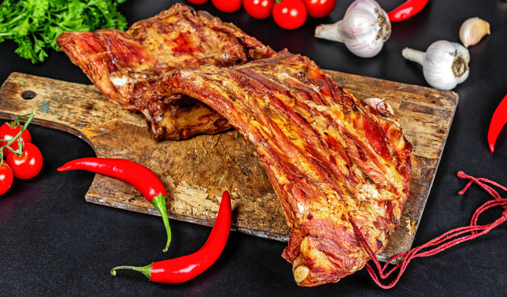 Копченые ребра на столе с красным перцем, чесноком и помидорами
