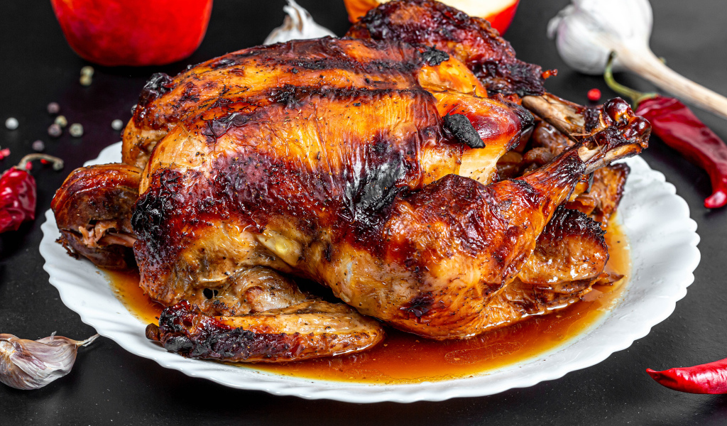 Вкусная запеченная курица на белой тарелке на столе с овощами