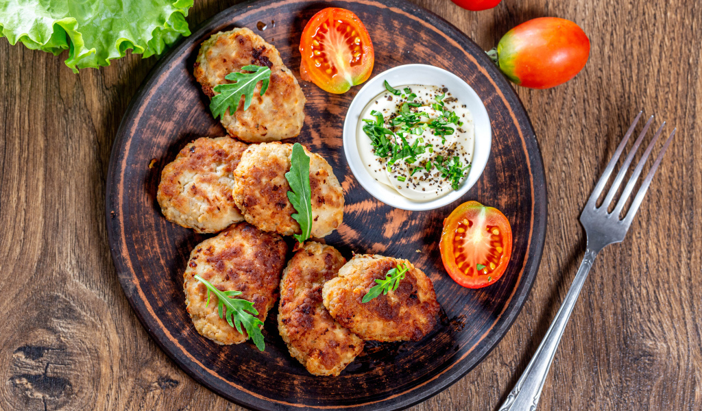 Вкусные котлеты на столе с соусом и помидорами