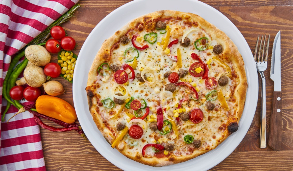 Аппетитная вкусная пицца на столе с овощами 