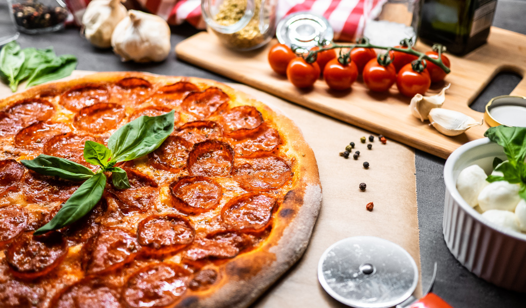 Пицца пепперони на столе с овощами и специями