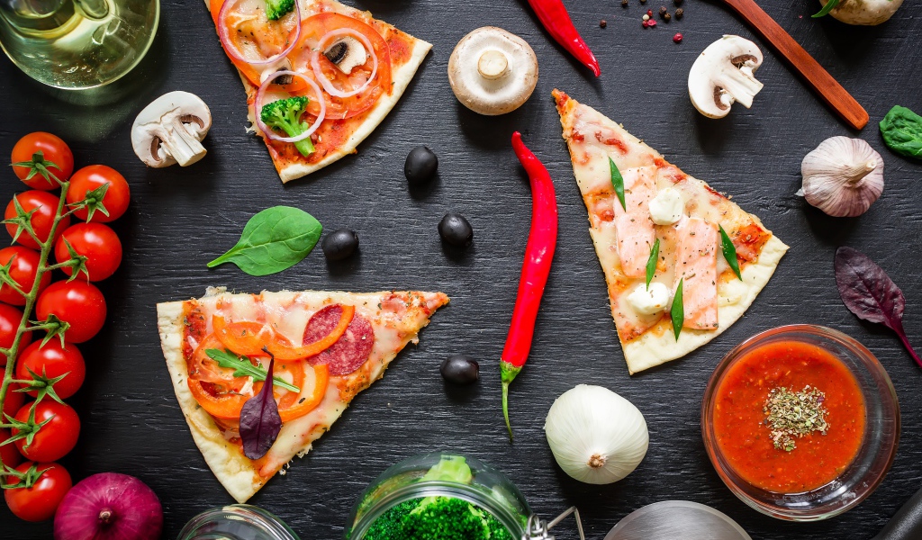 Куски пиццы на столе с овощами и соусом