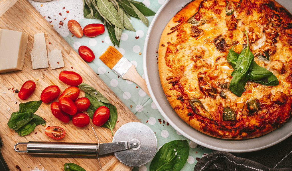 Румяная пицца на столе с сыром и помидорами