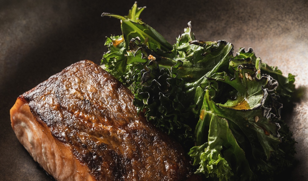 Кусок запеченной рыбы с листьями салата в сковороде 