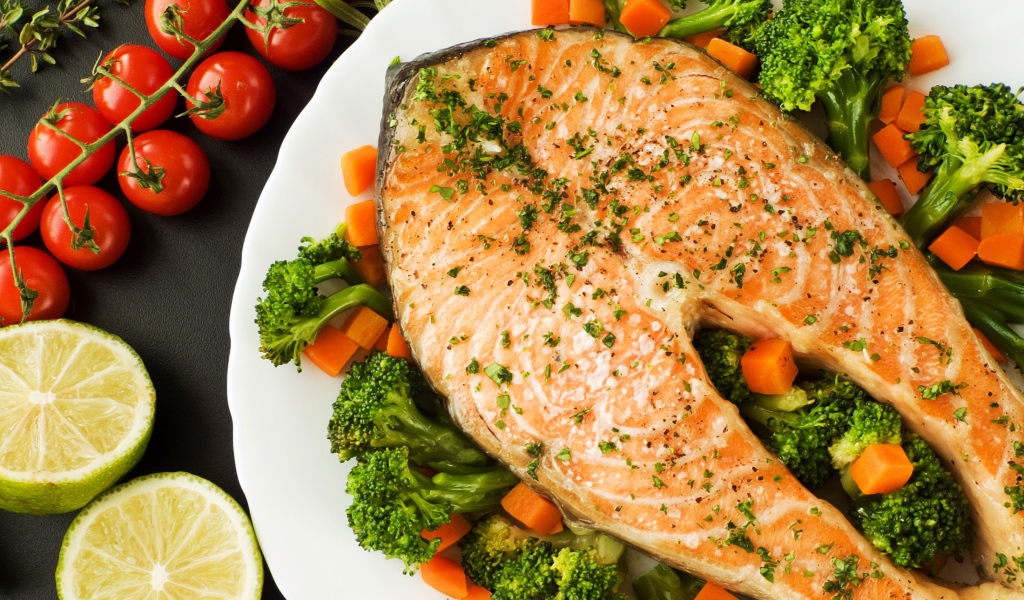 Кусок красной рыбы на тарелке с морковью и брокколи 