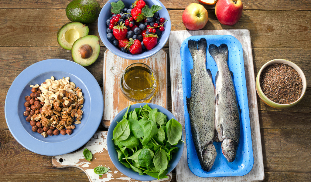 Fresh fish on a table with nuts, basil and berries