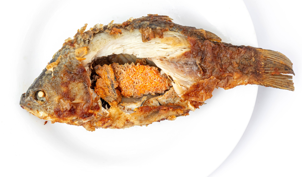 Жареная рыба с икрой внутри на белом фоне