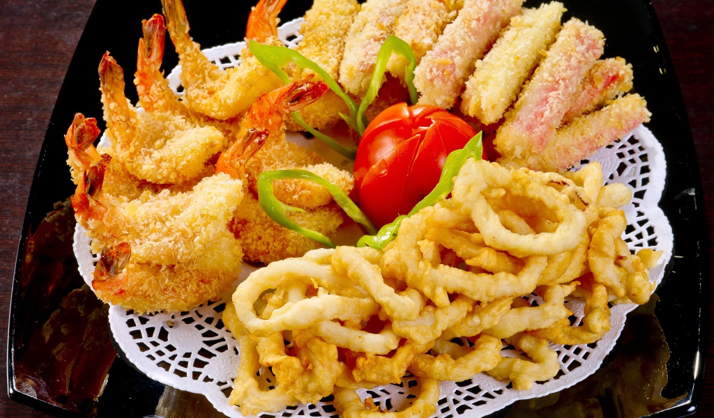 Морепродукты в кляре на тарелке с помидором