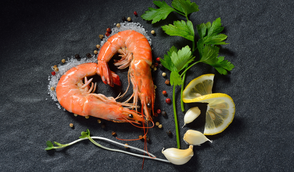 Сердце из креветок на сером столе с лимоном и веточкой петрушки 