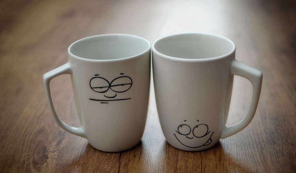 Две белые кружки с рисунками на столе 