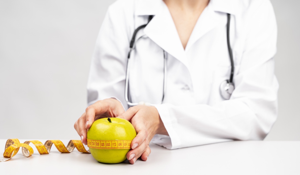 Женщина врач измеряет яблоко сантиметром 