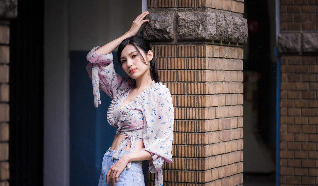 Красивая девушка азиатка стоит у кирпичной колонны 