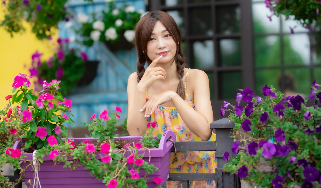 Милая азиатка стоит у кашпо с цветами петунии 