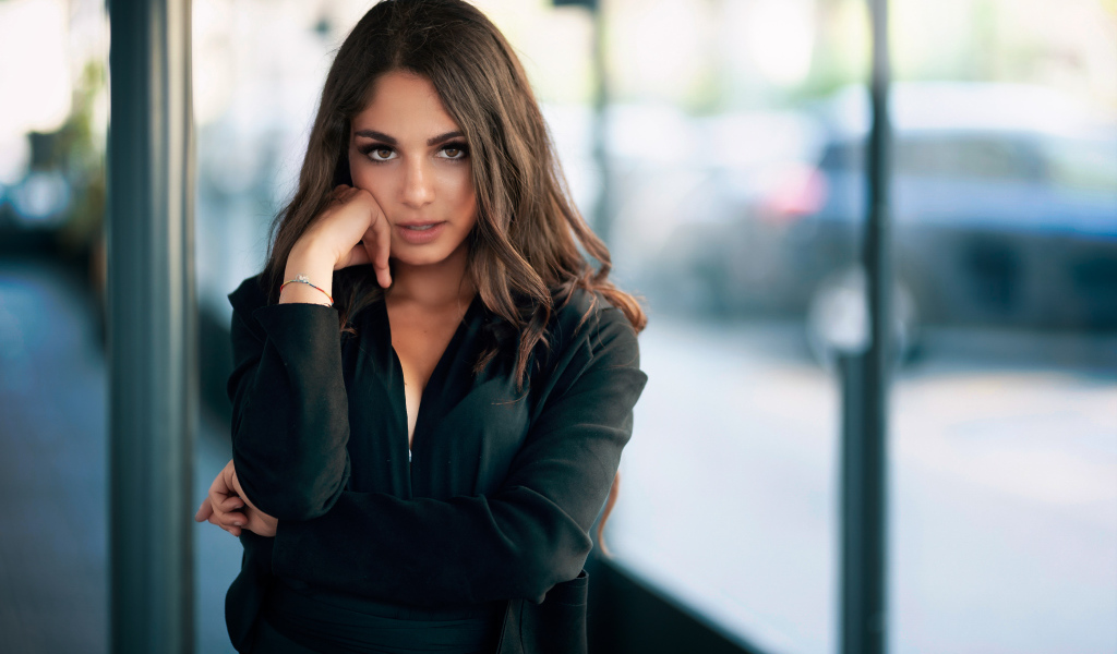 Милая девушка в черном наряде стоит на остановке