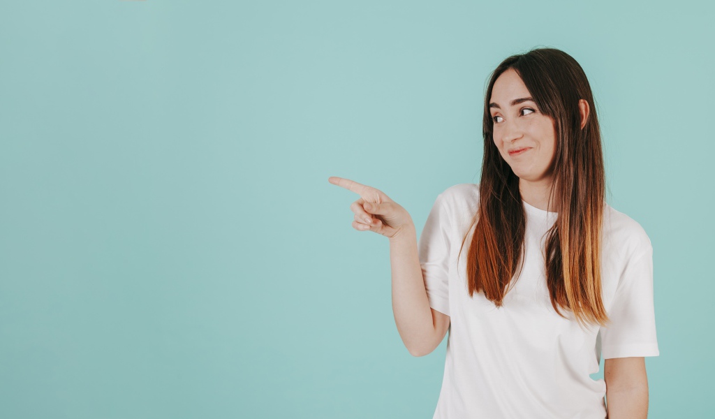 Девушка в белой футболке показывает на кого то пальцем