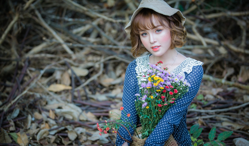 Молодая девушка азиатка с букетом цветов сидит на ветках