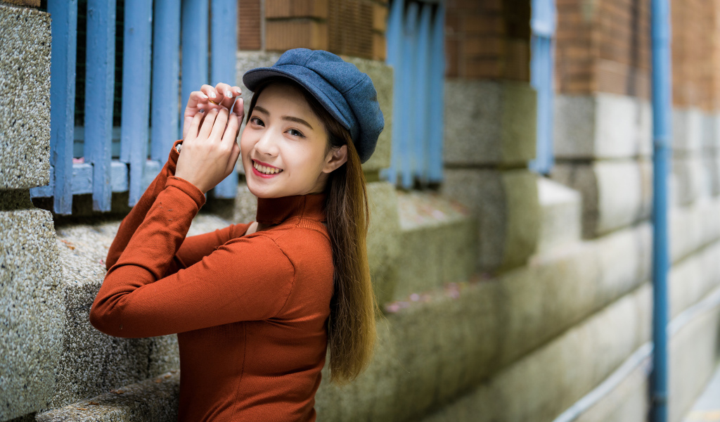 Девушка азиатка в кепке на стенке 