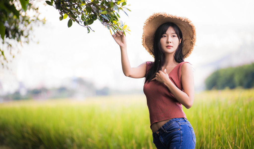 Девушка азиатка в шляпе на поле 