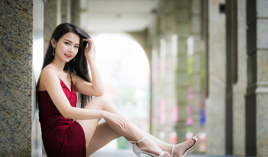 Девушка азиатка в красном платье сидит на полу