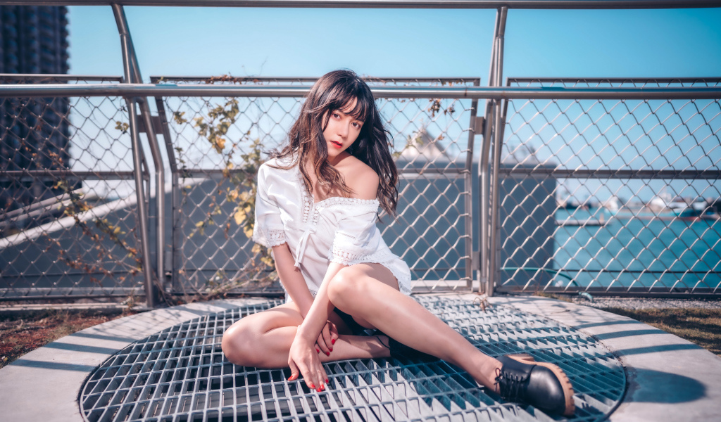 Девушка азиатка в белом наряде сидит на сетке