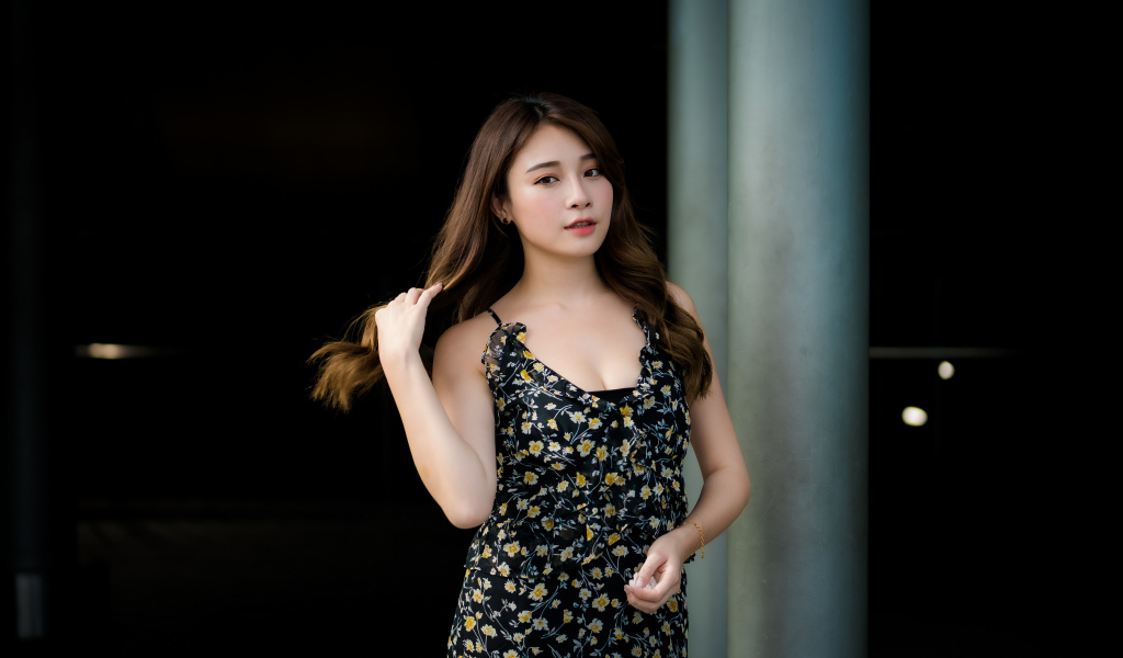 Девушка азиатка в платье трогает волосы 