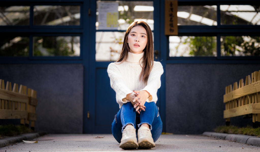 Девушка азиатка в белом свитере видит на полу 