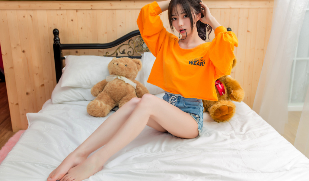 Девушка азиатка на кровати с игрушками