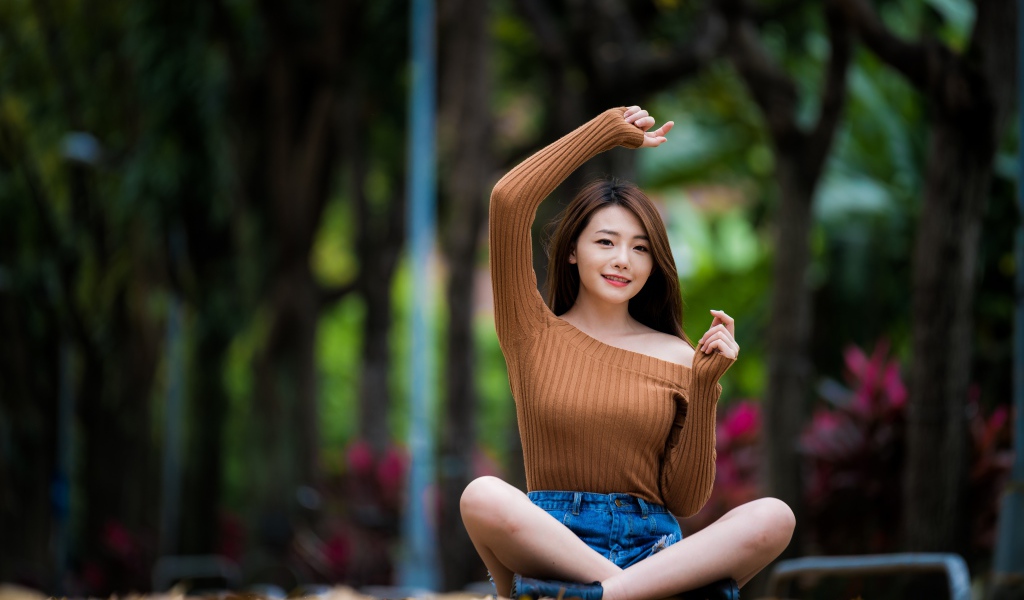 Девушка азиатка сидит в позе лотоса в парке 