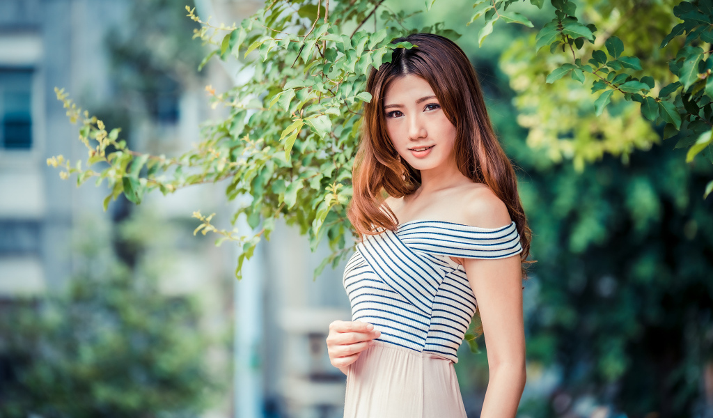 Девушка азиатка стоит под деревом в парке 