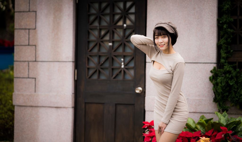 Красивая азиатка в платье стоит у двери 