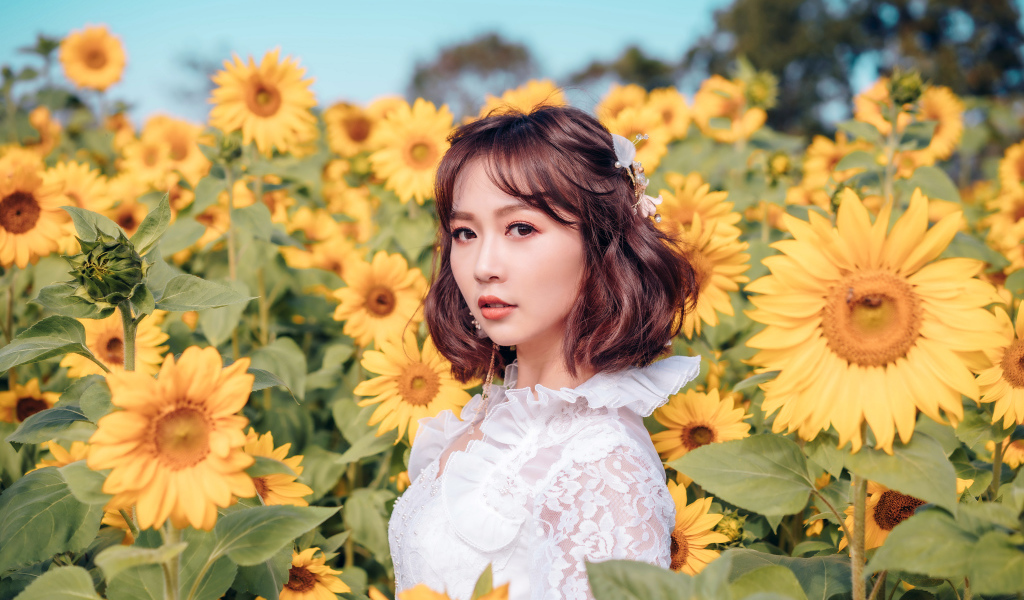 Красивая девушка азиатка в белом платье на поле с подсолнухами