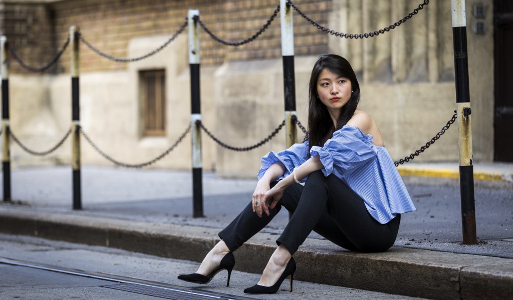 Красивая девушка азиатка в черных брюках сидит на земле