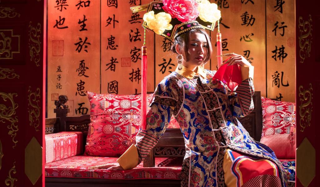 Красивая девушка азиатка в национальном костюме на диване