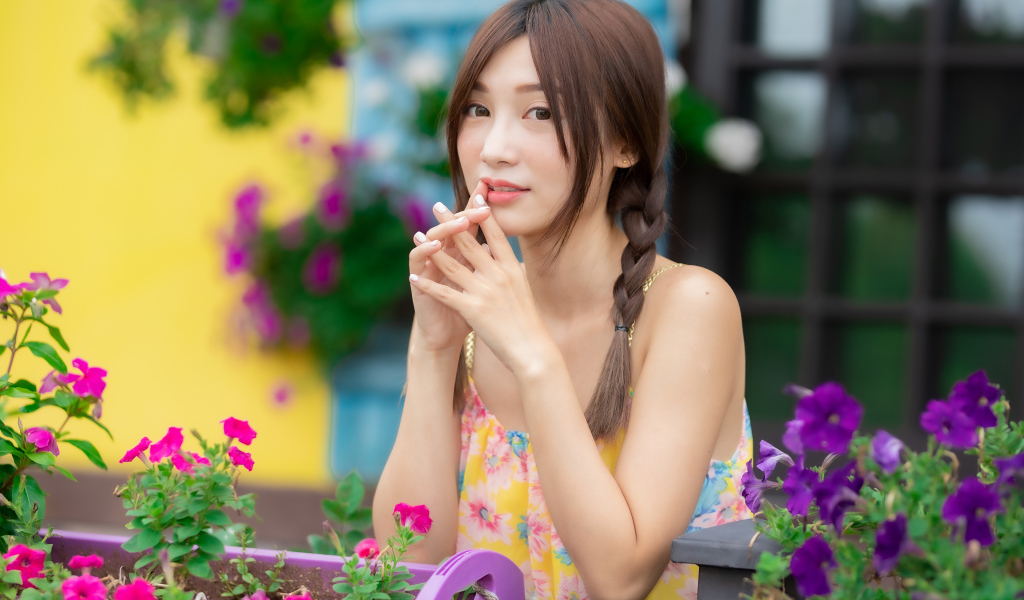 Красивая девушка Азиатка у цветов петунии