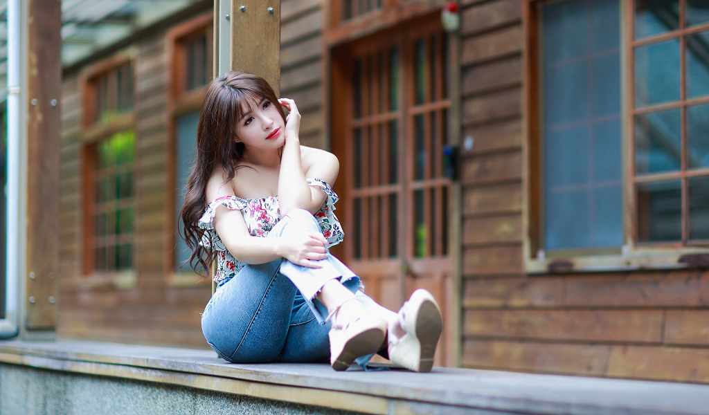 Красивая девушка азиатка сидит у дома