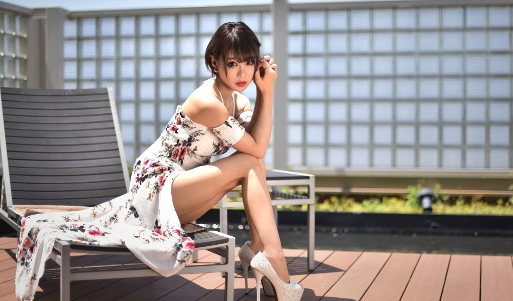 Красивая девушка азиатка сидит на шезлонге 
