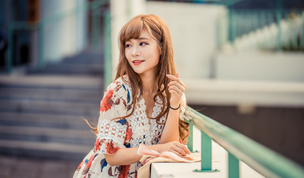 Красивая девушка азиатка стоит у перил 