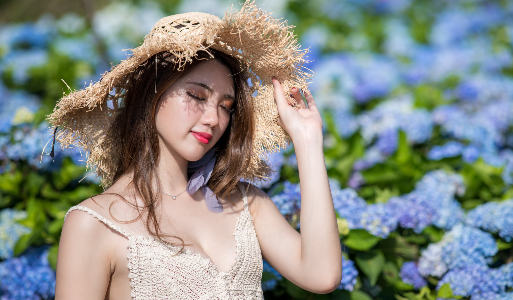 Красивая девушка азиатка с закрытыми глазами на фоне цветов гортензии