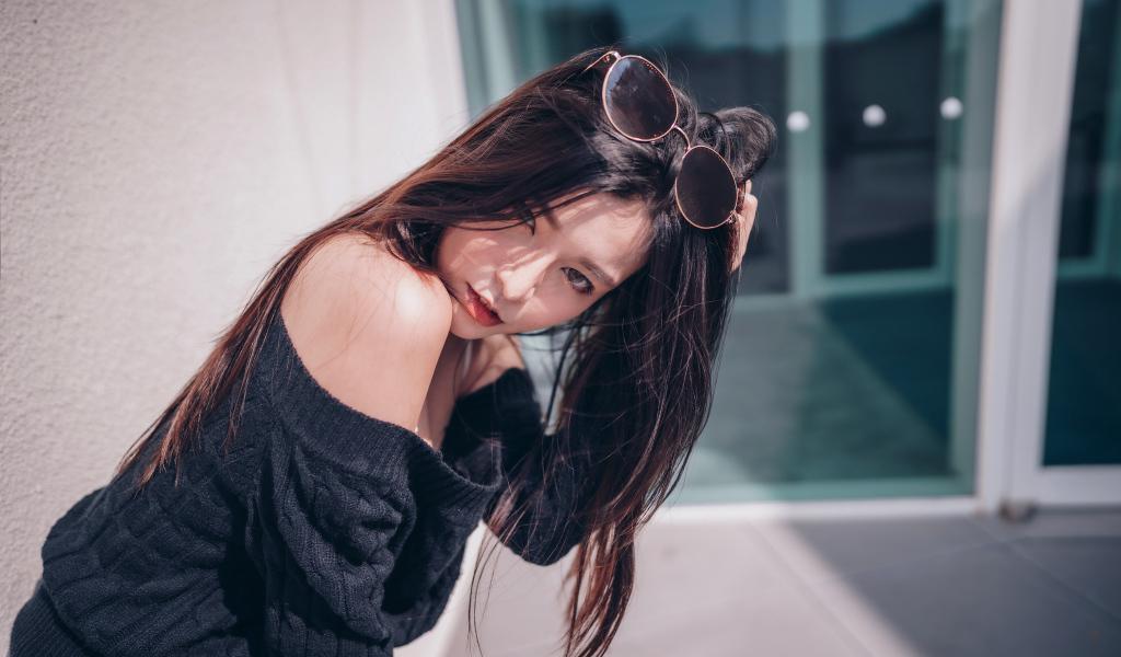 Красивая азиатка в черном свитере с солнечными очками на голове 